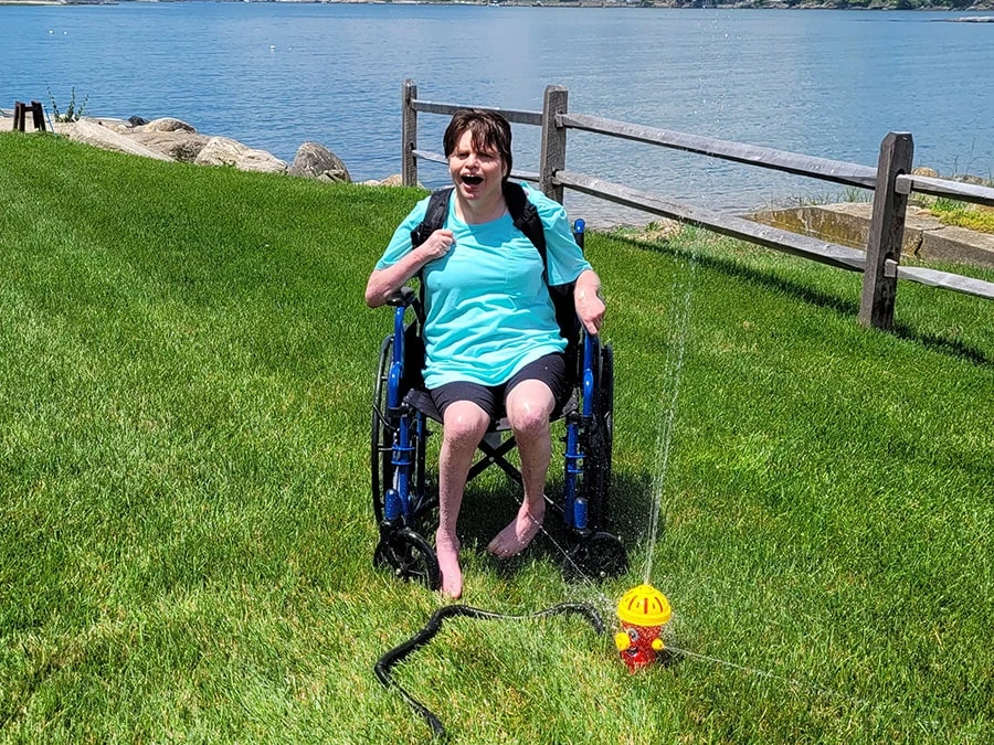 disabled woman enjoying a fire hydrant sprinkler by the beach