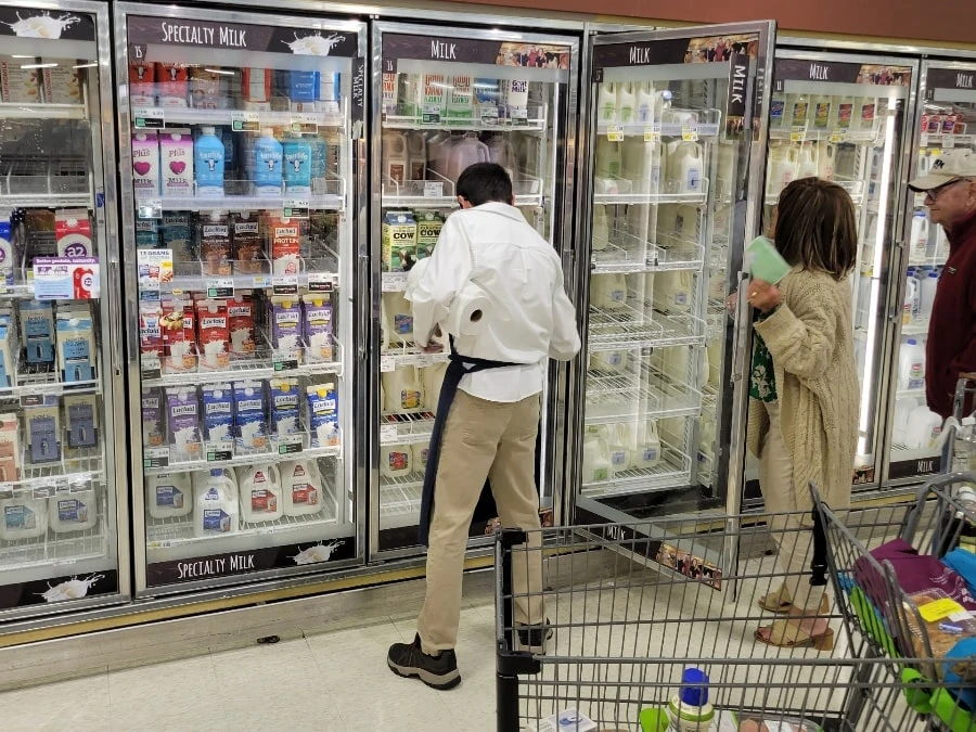 man with back to the camera cleaning refrigerator shelves
